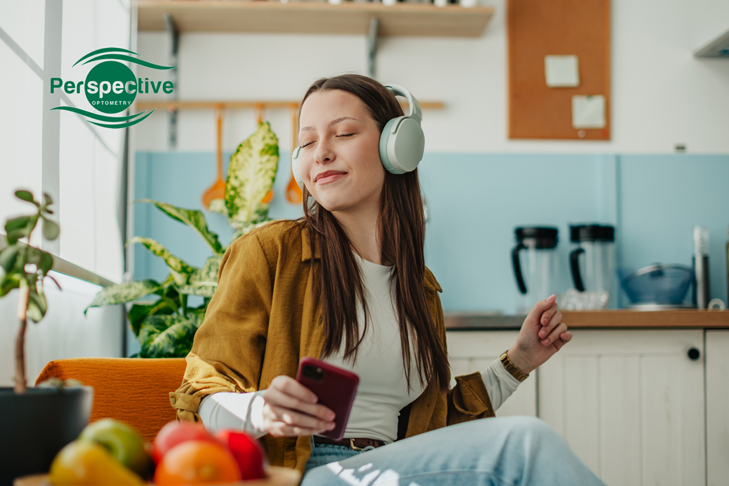 Woman practicing visual hygiene by closing her eyes while listening to music to relieve digital eye strain.